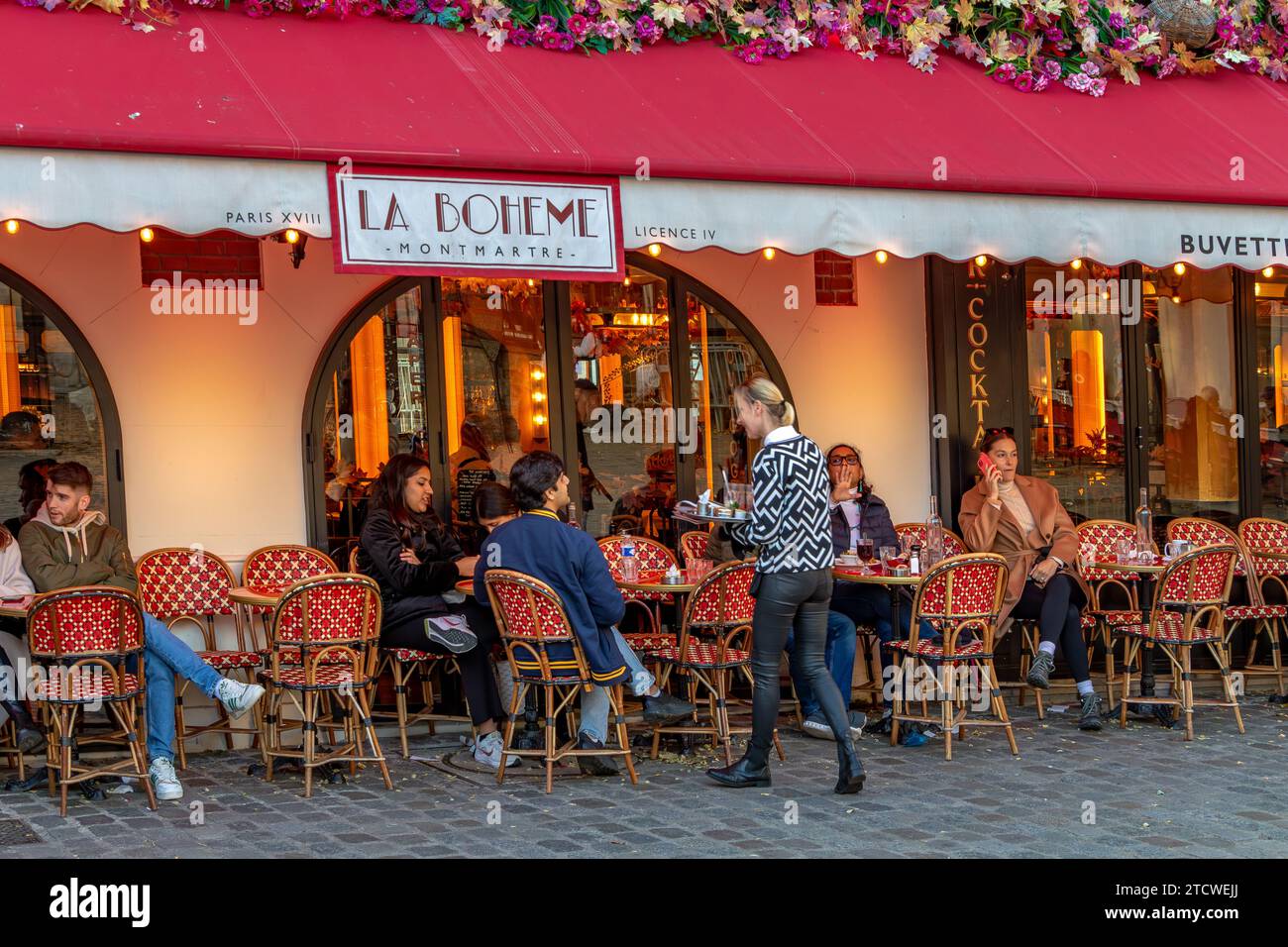 Une serveuse servant une table à la Bohème Montmartre , un restaurant français à Montmartre dans le 18e arrondissement de Paris, France Banque D'Images