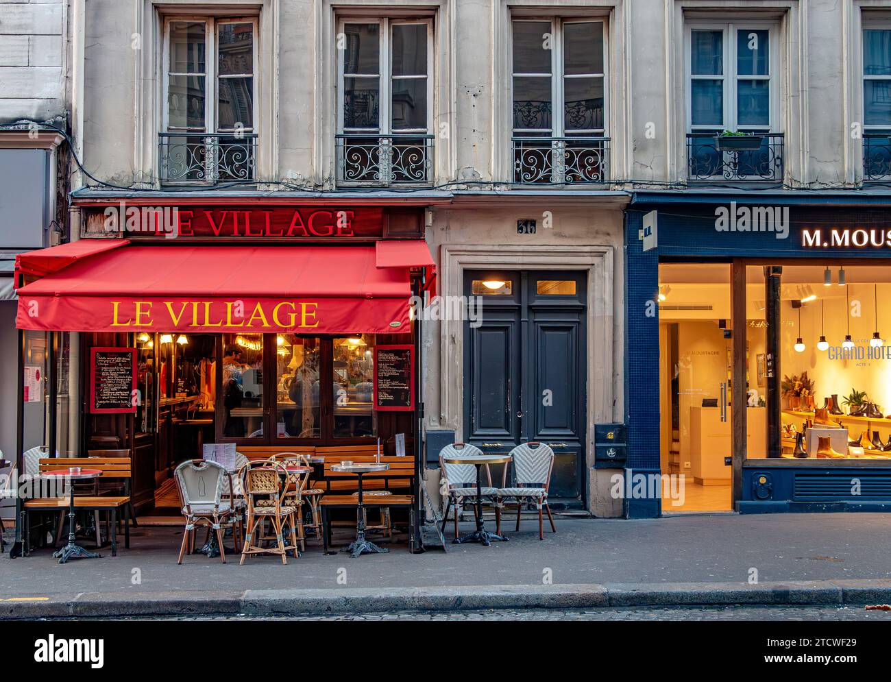 Tables et chaises devant le Village, un petit restaurant, un café rue des Abbesses, Montmartre dans le 18e arrondissement de Paris, France Banque D'Images