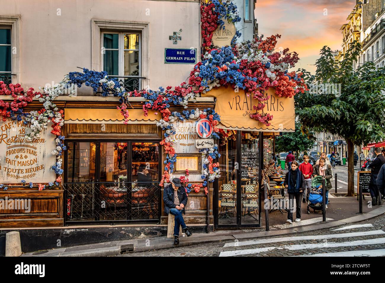 Un homme debout devant le vrai Paris, un bisto animé sur la rue Abbesses, Montmartre dans le 18e arrondissement de Paris, France Banque D'Images
