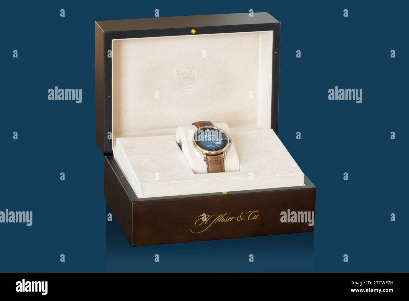 Présentoir de boîtes avec H. Moser et Cie. Venturer Big Date Purity Blue fume montre-bracelet du fabricant suisse de montres de luxe. Isolé sur fond bleu Banque D'Images