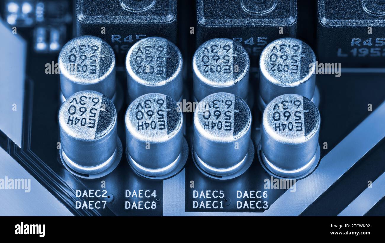 Gros plan un groupe de condensateurs électrolytiques en aluminium sur le détail de PCB dans le ton bleu. Condensateurs ou inducteurs composants électroniques sur carte de circuit imprimé. Banque D'Images