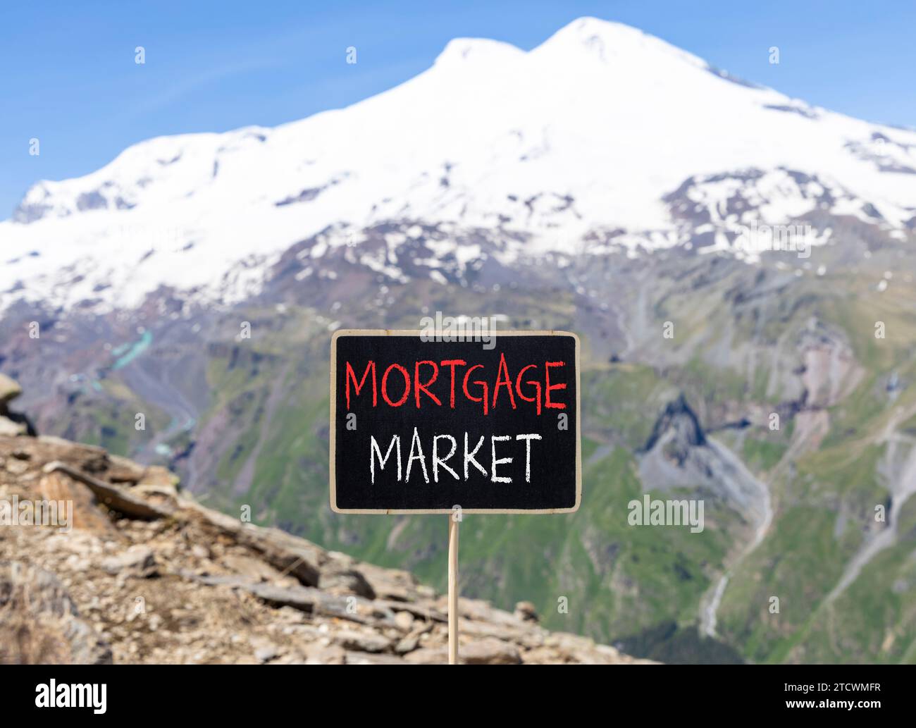 Symbole du marché hypothécaire. Mots concept marché hypothécaire sur beau tableau noir de craie. Belle montagne Elbrus fond de ciel bleu. Or Banque D'Images