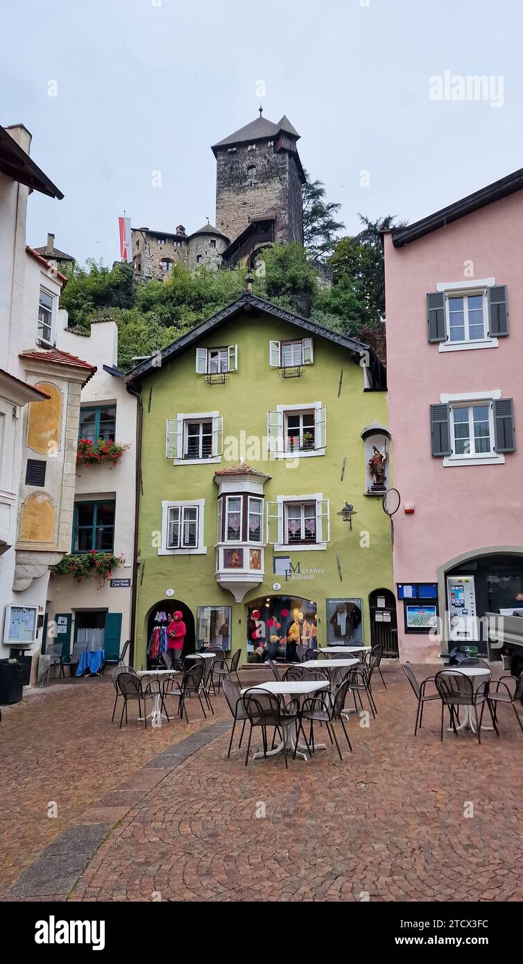 Maisons colorées sur une place dans la ville médiévale de Chiusa (allemand : Klausen) dans le Tyrol du Sud. Une tour de défense massive est visible au-dessus d'elle sur une colline. Banque D'Images