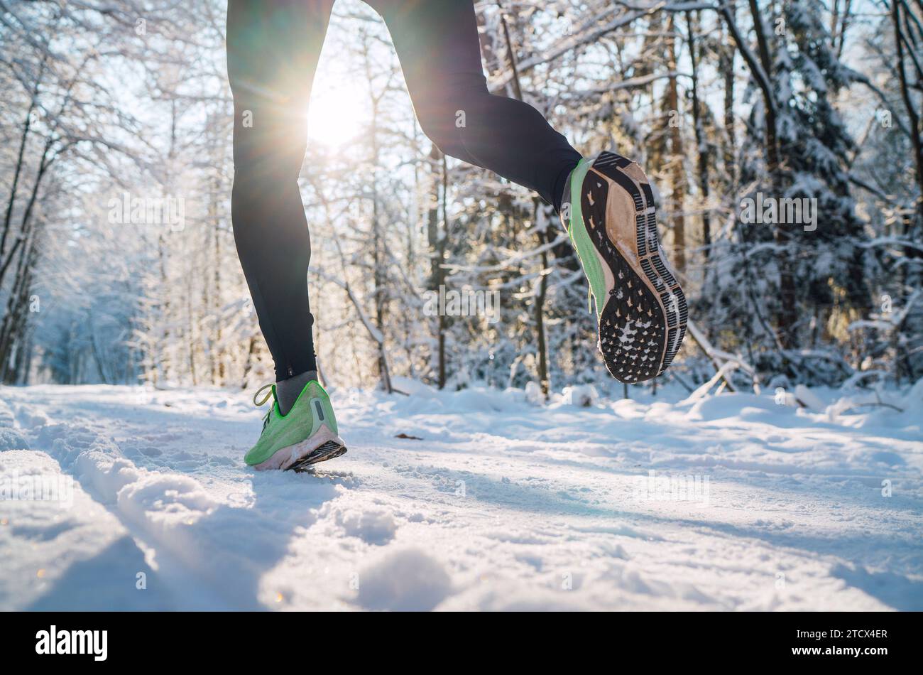 Chaussures de course semelle gros plan image des pieds de jogging d'hiver dans les baskets de course sur le chemin enneigé du parc pendant la journée ensoleillée. Vue arrière de la semelle. Banque D'Images