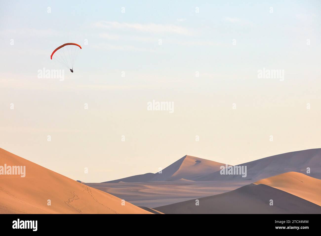 Paraglading dans le désert de Huacachina au coucher du soleil, ICA, Pérou. Banque D'Images