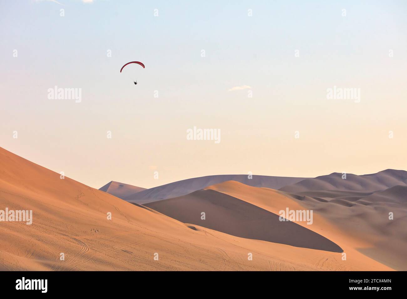 Paraglading dans le désert de Huacachina au coucher du soleil, ICA, Pérou. Banque D'Images
