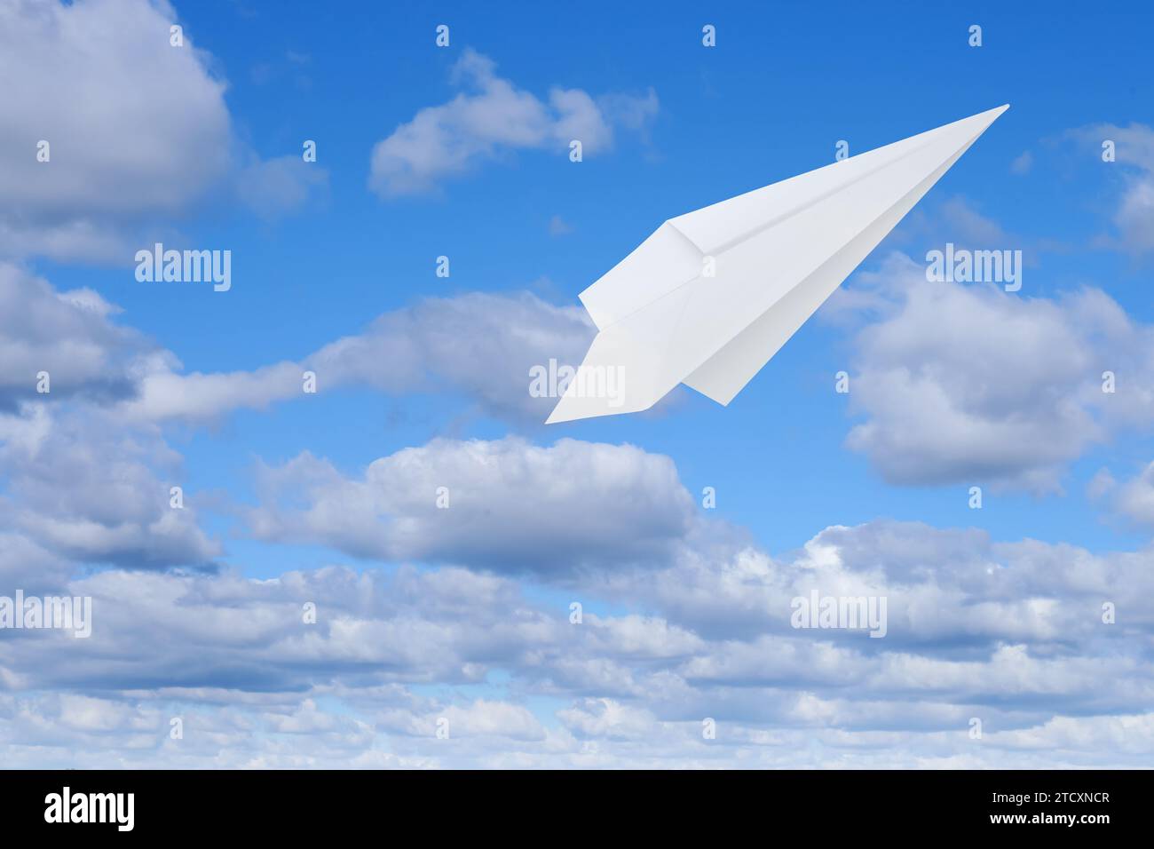 Avion en papier blanc volant dans le ciel bleu avec des nuages avec des nuages Banque D'Images