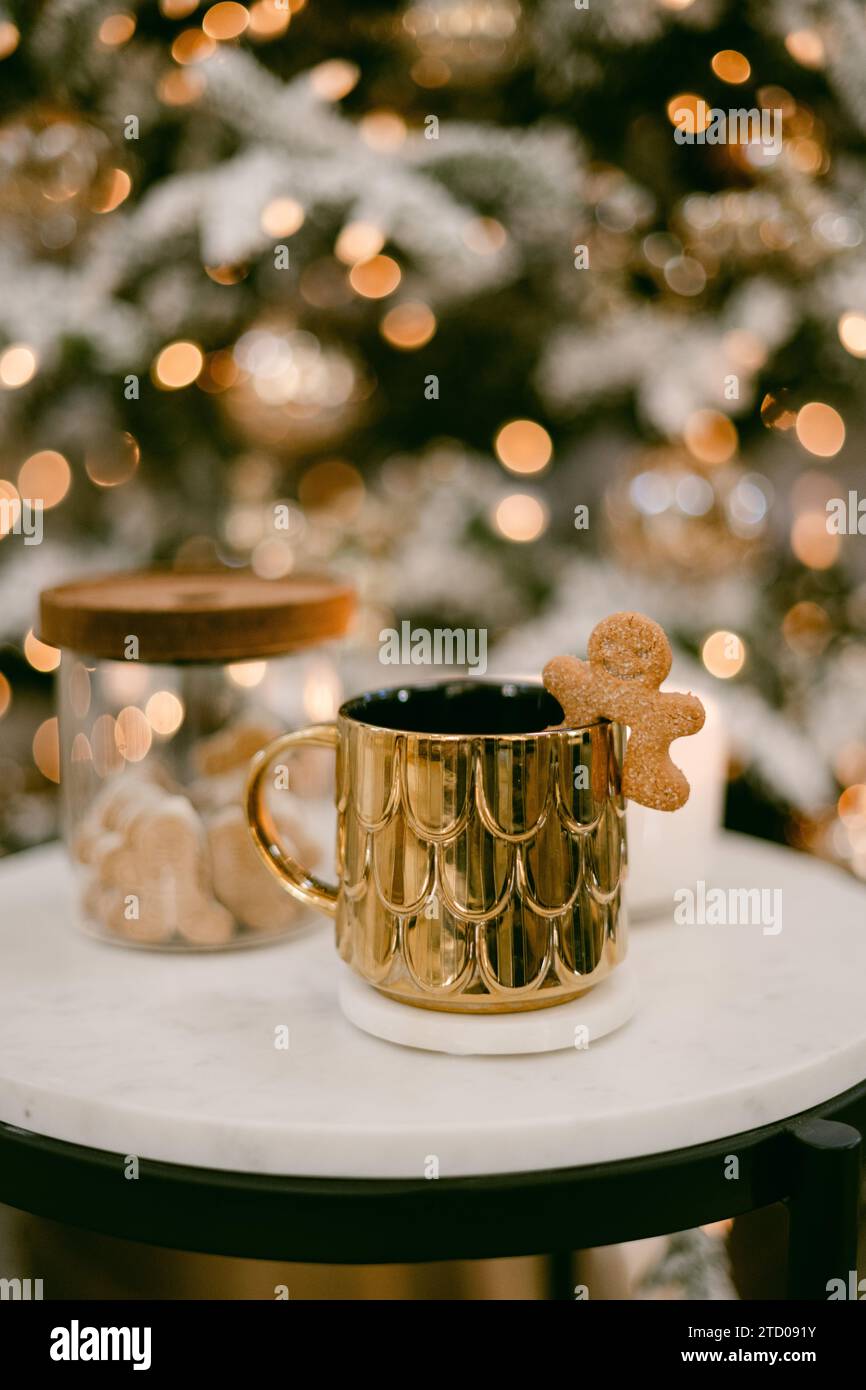 Tasse à café dorée avec lumières de noël en arrière-plan Banque D'Images