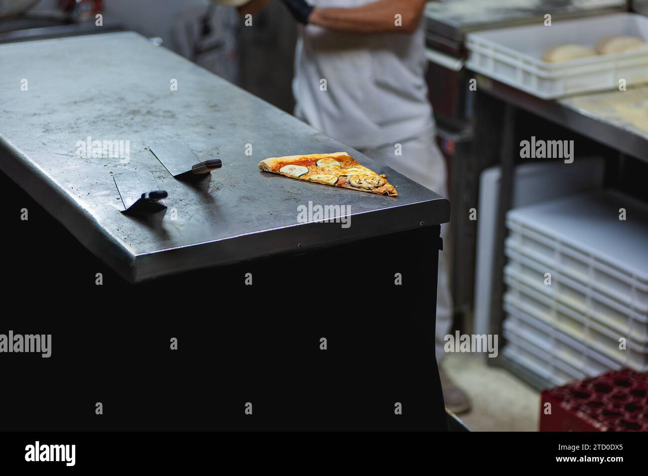 Tranche de pizza fraîchement cuite avec des spatules en acier sur le comptoir métallique dans la cuisine du restaurant Banque D'Images