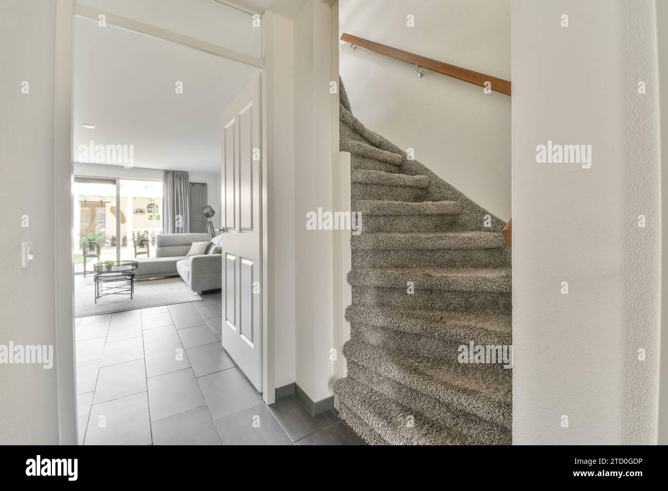 Escalier en moquette grise menant à l'étage supérieur dans le couloir relié au salon à la luxueuse maison blanche Banque D'Images