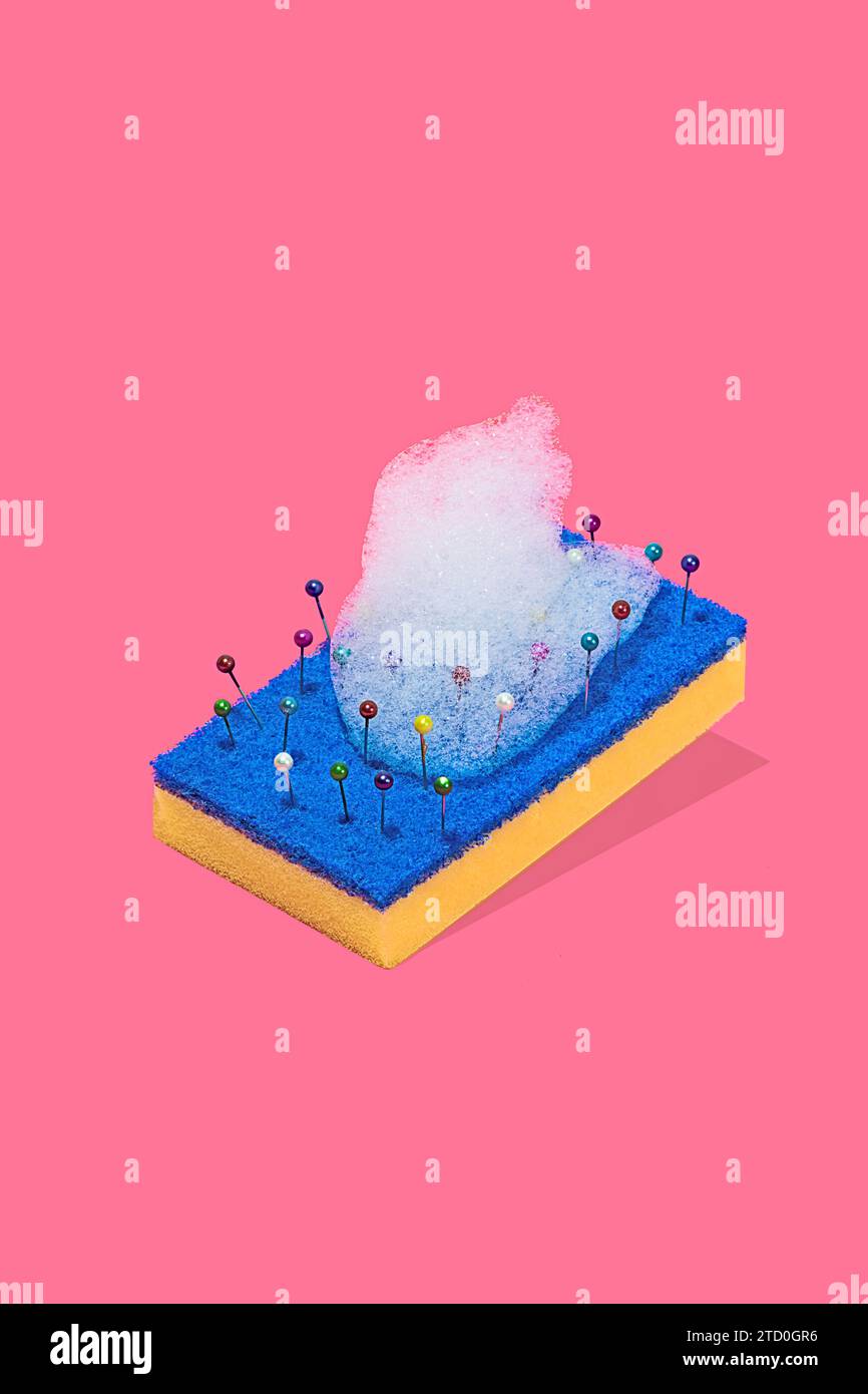 Une représentation créative d'un tampon à récurer bleu et jaune avec des épingles colorées et des bulles de mousse sur un fond rose Banque D'Images