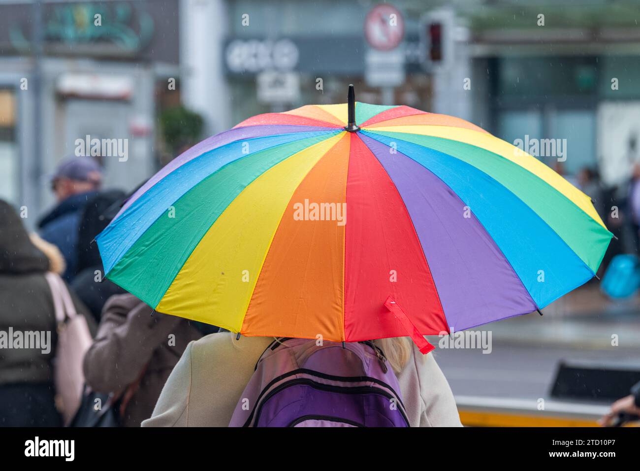 Femme avec un parapluie coloré pendant une douche de pluie à Cork City, Irlande. Banque D'Images