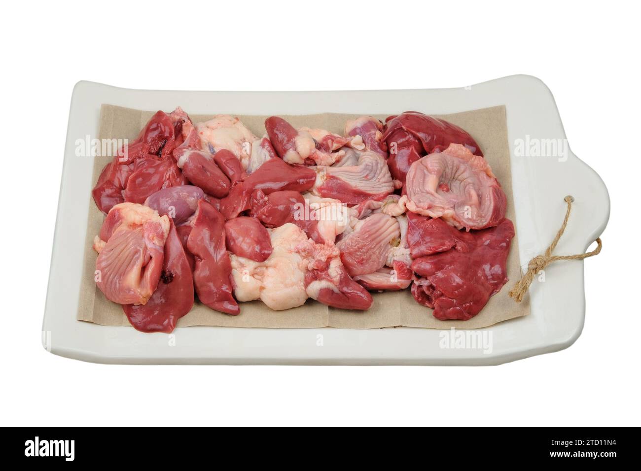 Abats de poulet sur une planche en céramique isolé sur fond blanc. Les estomacs de poulet, les coeurs et les foies sont préparés pour la cuisson. Viande crue. Banque D'Images