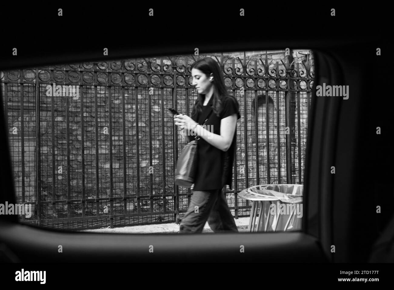 Femme marchant dans la rue en utilisant le téléphone portable, vue de l'intérieur d'une voiture, Paris, France Banque D'Images