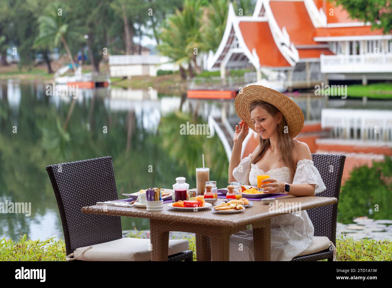 Femme profitant du petit déjeuner à la station tropicale avec vue sur le lac. Banque D'Images