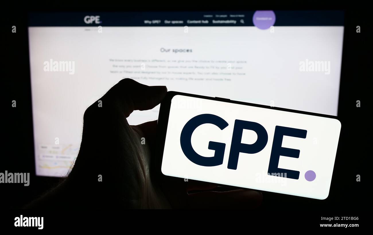 Personne tenant un smartphone avec le logo de la société immobilière britannique Great Portland Estates plc (GPE) devant le site Web. Concentrez-vous sur l'affichage du téléphone. Banque D'Images