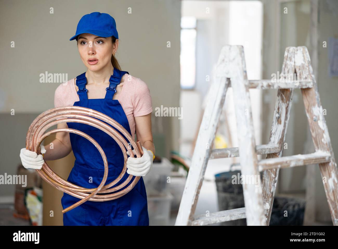Portrait de femme constructeur dans des combinaisons bleues avec des tubes de chauffage au sol dans les mains Banque D'Images