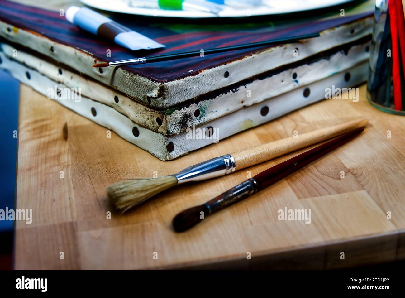 de vieilles toiles avec un ensemble de pinceaux et quelques tubes de peintures à l'huile reposent sur une table en bois Banque D'Images