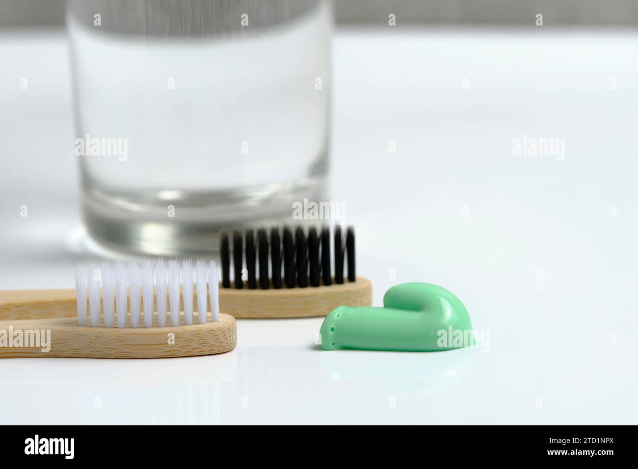 Eau en verre, deux brosses à dents en bois et dentifrice vert de conifères dans la salle de bain Banque D'Images