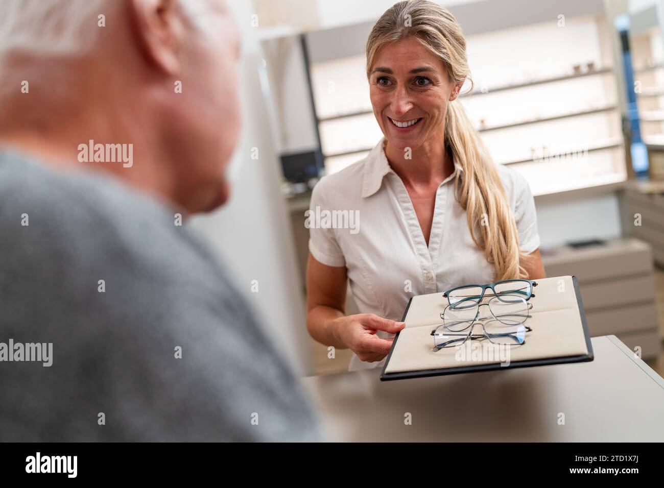 Optométriste présentant des lunettes à une cliente âgée dans un magasin d'optique. Banque D'Images