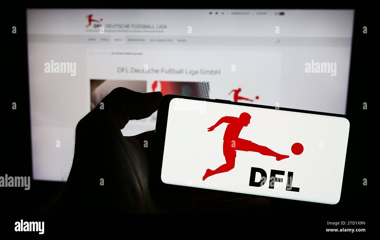 Personne détenant un téléphone portable avec le logo de la société allemande de football DFL Deutsche Fußball Liga GmbH devant la page Web. Concentrez-vous sur l'affichage du téléphone. Banque D'Images