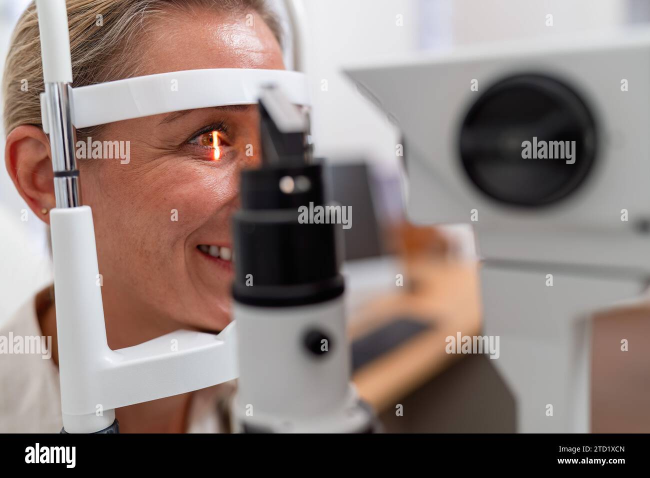 Femme souriante lors d'un examen oculaire avec réflexion rétinienne à lampe à fente visible à la clinique d'ophtalmologie. Gros plan. Concept de santé et de médecine Banque D'Images