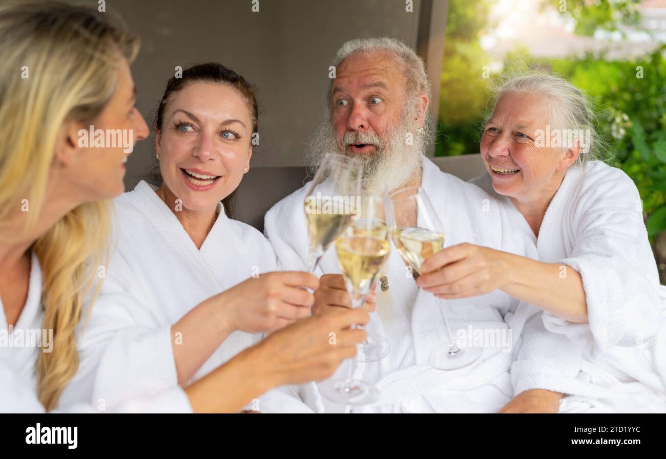 Deux femmes et un couple d'aînés riant et grillant avec des verres à champagne dans un hôtel spa wellnes Banque D'Images