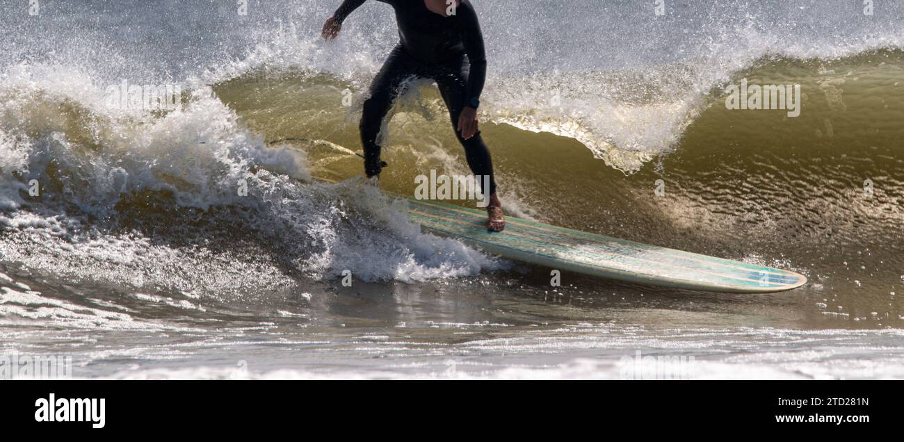 Homme portant une combinaison surfant avec une longue planche de surf à Giglo Beach sur long Island. Banque D'Images