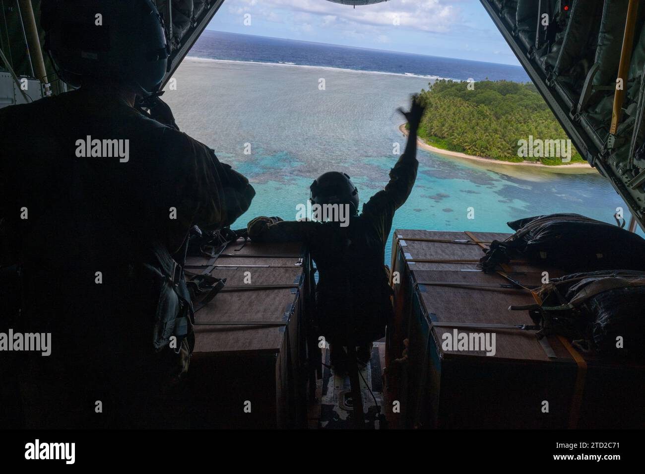 Oneop, Îles Mortlock, États fédérés de Micronésie. 03 décembre 2023. Ian Munoz, chef de chargement de l'US Air Force, agite avant de larguer des paquets de fret humanitaire par parachute depuis un C-130J Super Hercules de l'US Air Force lors de l'opération Christmas Drop, le 3 décembre 2023 à Oneop, Mortlock Islands, Micronésie. L’opération Christmas Drop est la plus ancienne mission humanitaire et de secours en cas de catastrophe qui fournit 71 000 livres de nourriture, de cadeaux et de fournitures pour aider les communautés insulaires éloignées du Pacifique Sud. Crédit : SRA Brooklyn Golightly/US Airforce photo/Alamy Live News Banque D'Images