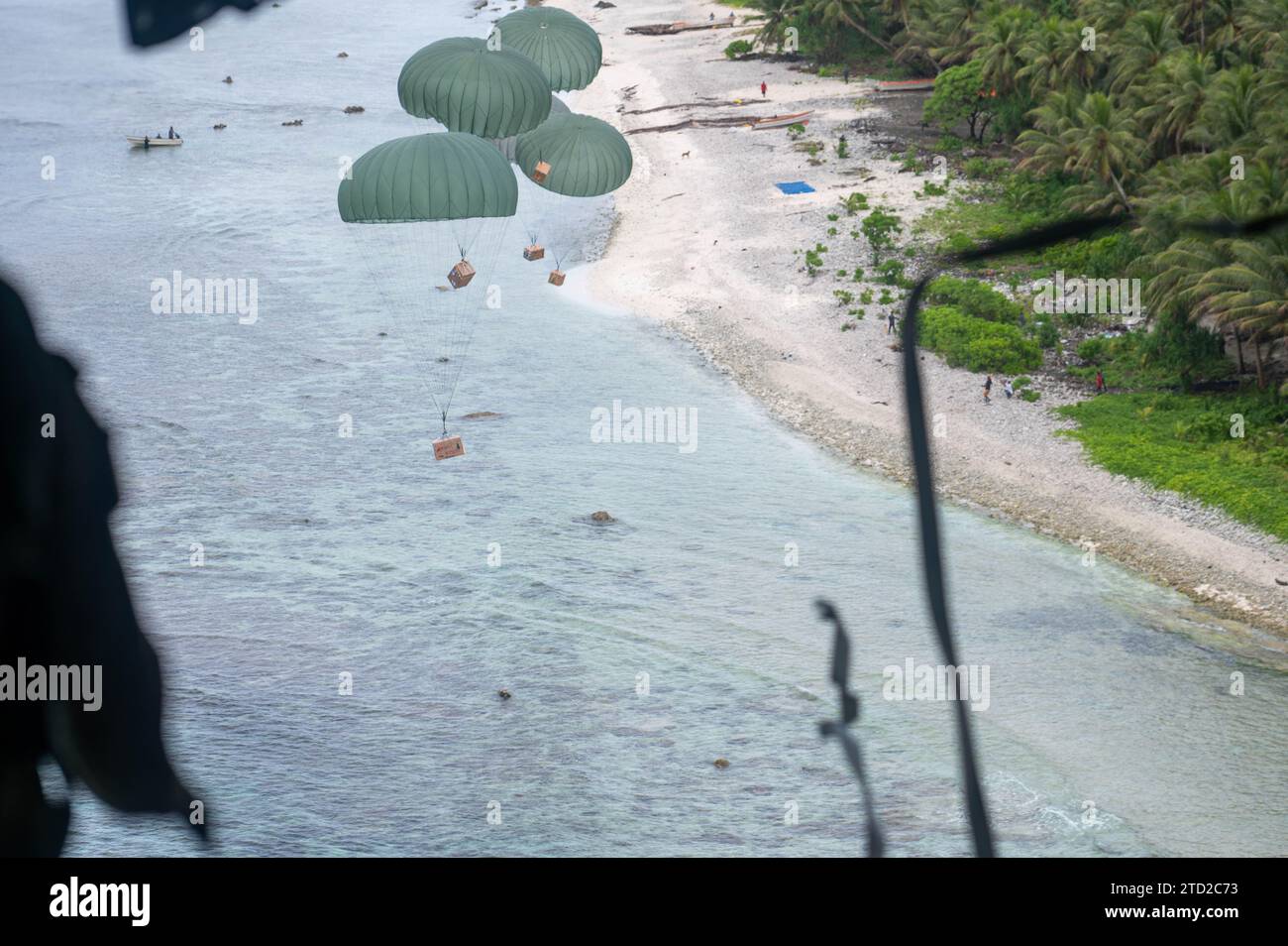 Atoll de Losap, îles Mortlock supérieures, États fédérés de Micronésie. 04 décembre 2023. Des paquets humanitaires flottent vers un lagon en parachute à partir d'un avion C-130J Super Hercules de l'US Air Force, lors de l'opération Christmas Drop, le 4 décembre 2023 dans l'atoll de Losap, dans les îles Upper Mortlock, en Micronésie. L’opération Christmas Drop est la plus ancienne mission humanitaire et de secours en cas de catastrophe qui fournit 71 000 livres de nourriture, de cadeaux et de fournitures pour aider les communautés insulaires éloignées du Pacifique Sud. Crédit : Airman Allon Lapaix/US Airforce photo/Alamy Live News Banque D'Images