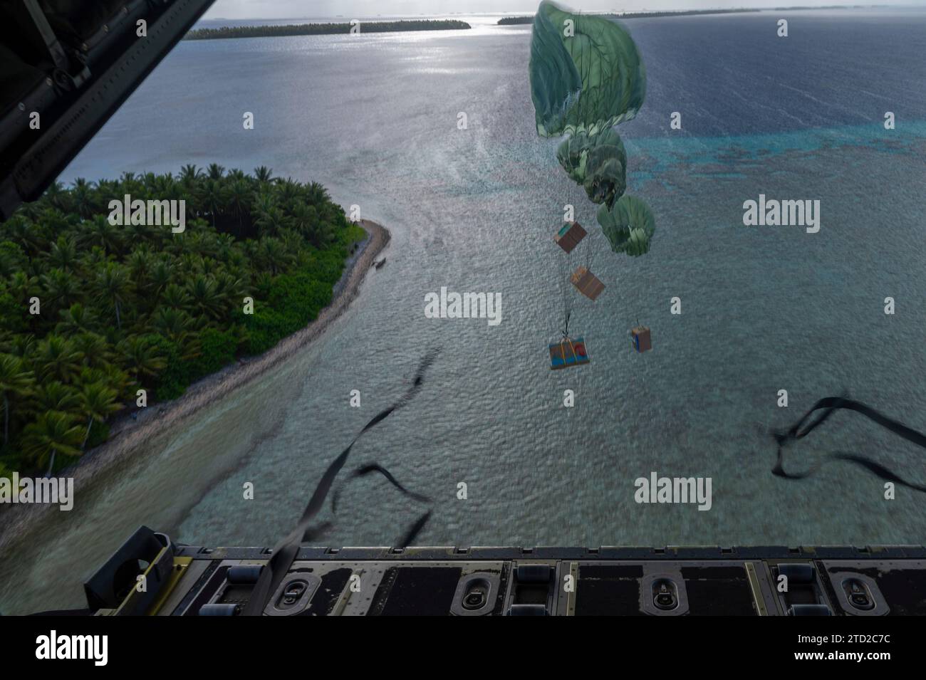 Oneop, Îles Mortlock, États fédérés de Micronésie. 03 décembre 2023. Des paquets humanitaires parachutent vers un lagon à partir d'un avion Super Hercules C-130J de l'US Air Force affecté au 36e Escadron de transport aérien expéditionnaire, lors de l'opération Christmas Drop, le 3 décembre 2023 à Oneop, Mortlock Islands, Micronésie. L’opération Christmas Drop est la plus ancienne mission humanitaire et de secours en cas de catastrophe qui fournit 71 000 livres de nourriture, de cadeaux et de fournitures pour aider les communautés insulaires éloignées du Pacifique Sud. Crédit : SRA Brooklyn Golightly/US Airforce photo/Alamy Live News Banque D'Images