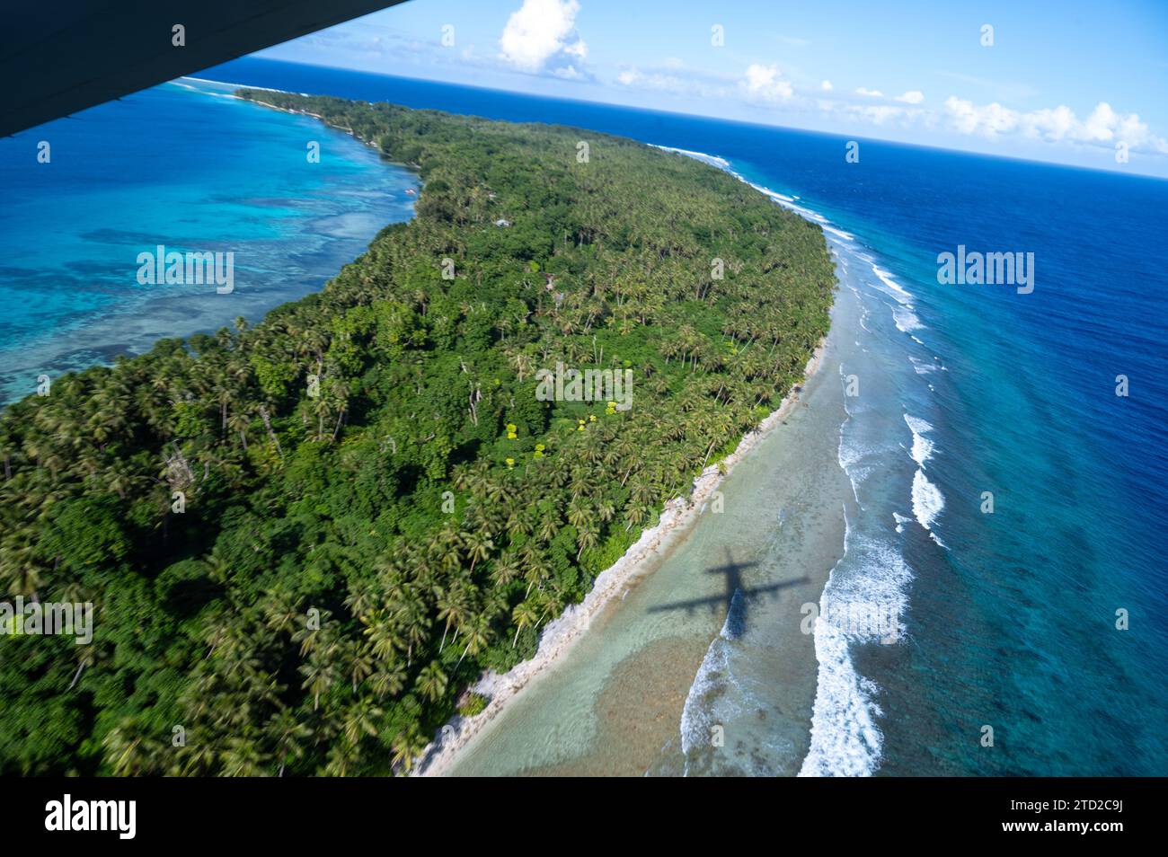 Lukunor, Îles Mortlock, États fédérés de Micronésie. 03 décembre 2023. L'ombre d'un avion C-130J Super Hercules de l'US Air Force est projetée sur le lagon avant de larguer des paquets humanitaires par parachute lors de l'opération Christmas Drop, le 3 décembre 2023 à Lukunor, Mortlock Islands, Micronésie. L’opération Christmas Drop est la plus ancienne mission humanitaire et de secours en cas de catastrophe qui fournit 71 000 livres de nourriture, de cadeaux et de fournitures pour aider les communautés insulaires éloignées du Pacifique Sud. Crédit : SRA Brooklyn Golightly/US Airforce photo/Alamy Live News Banque D'Images