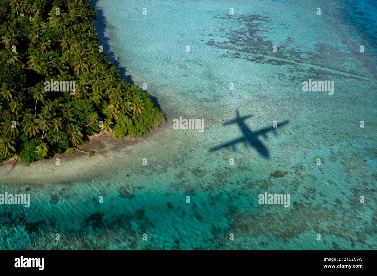 Oneop, Îles Mortlock, États fédérés de Micronésie. 03 décembre 2023. L'ombre d'un avion C-130J Super Hercules de l'US Air Force est projetée sur le lagon avant de larguer des paquets humanitaires par parachute lors de l'opération Christmas Drop, le 3 décembre 2023 à Oneop, Mortlock Islands, Micronésie. L’opération Christmas Drop est la plus ancienne mission humanitaire et de secours en cas de catastrophe qui fournit 71 000 livres de nourriture, de cadeaux et de fournitures pour aider les communautés insulaires éloignées du Pacifique Sud. Crédit : SRA Brooklyn Golightly/US Airforce photo/Alamy Live News Banque D'Images