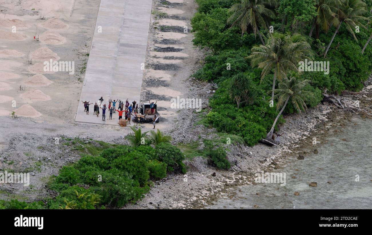 Îles Mortlock, États fédérés de Micronésie. 08 décembre 2023. Les insulaires se réjouissent après avoir récupéré des paquets de marchandises humanitaires largués par parachute depuis un avion C-130J Super Hercules de l'US Air Force, lors de l'opération Christmas Drop, le 8 décembre 2023 dans les États fédérés de Micronésie. L’opération Christmas Drop est la plus ancienne mission humanitaire et de secours en cas de catastrophe qui fournit 71 000 livres de nourriture, de cadeaux et de fournitures pour aider les communautés insulaires éloignées du Pacifique Sud. Crédit : SRA Lauren Clevenger/US Airforce photo/Alamy Live News Banque D'Images