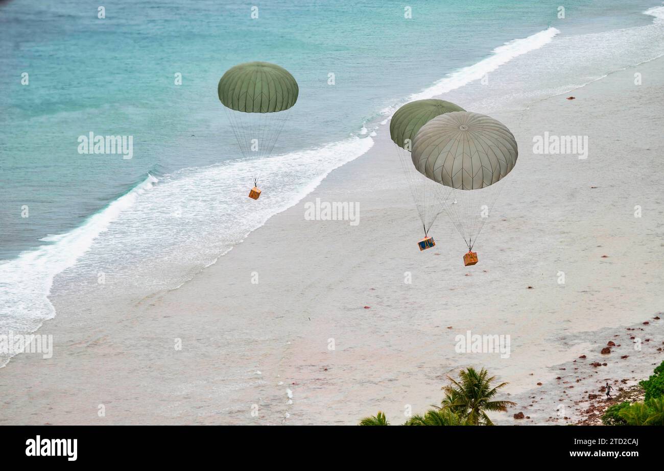 Îles Mortlock, États fédérés de Micronésie. 08 décembre 2023. Des paquets humanitaires flottent vers un lagon en parachute à partir d'un avion C-130J Super Hercules de l'US Air Force, lors de l'opération Christmas Drop, le 8 décembre 2023 dans les États fédérés de Micronésie. L’opération Christmas Drop est la plus ancienne mission humanitaire et de secours en cas de catastrophe qui fournit 71 000 livres de nourriture, de cadeaux et de fournitures pour aider les communautés insulaires éloignées du Pacifique Sud. Crédit : SRA Lauren Clevenger/US Airforce photo/Alamy Live News Banque D'Images