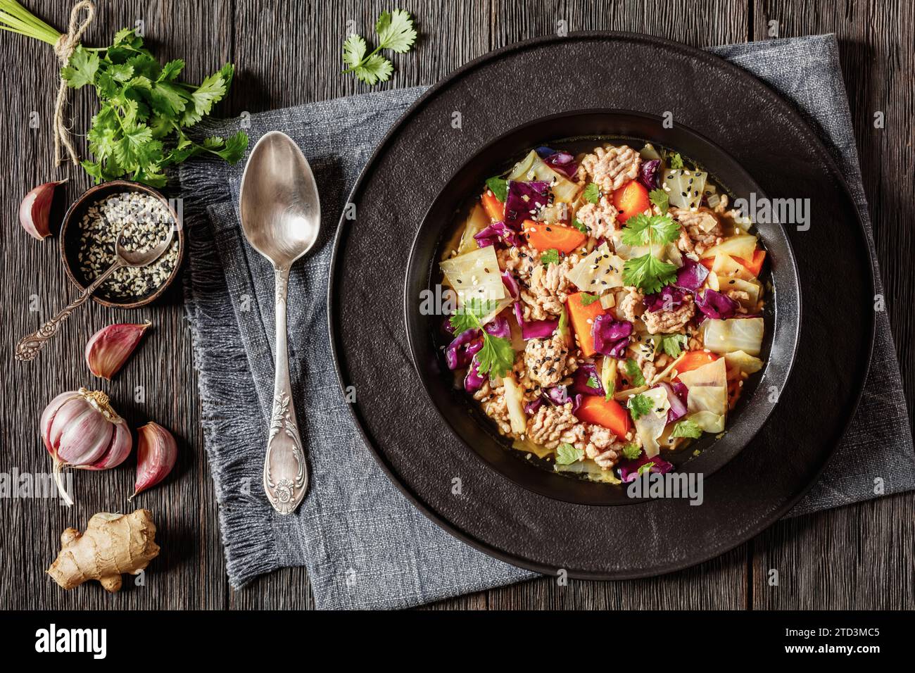 soupe au chou roulé aux œufs avec du porc haché et des légumes dans un bol noir sur une table en bois sombre avec des ingrédients, cuisine asiatique, vue horizontale d'en haut Banque D'Images