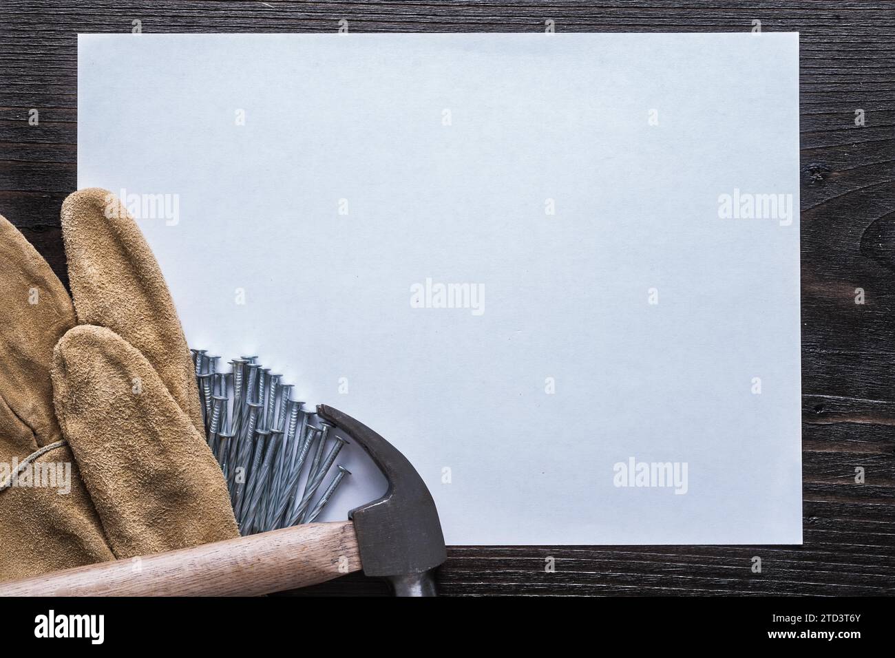 Feuille blanche de clous en acier de papier marteau à griffes et gants de protection en cuir sur le concept de construction d'espace copie de planche en bois vintage Banque D'Images