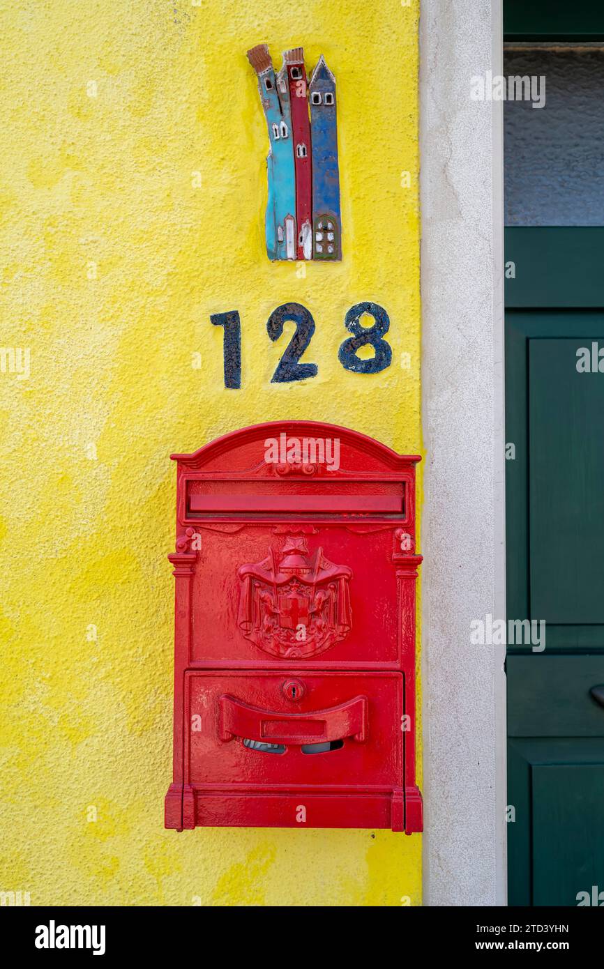 Boîte aux lettres artistique rouge sur un mur de maison jaune avec numéro de maison, maisons colorées sur l'île de Burano, Venise, Vénétie, Italie Banque D'Images