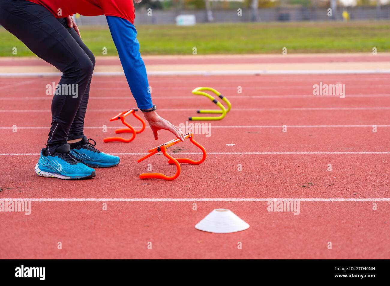 Photo recadrée de la partie inférieure d'une personne âgée préparant une piste de course avec des éléments d'entraînement Banque D'Images