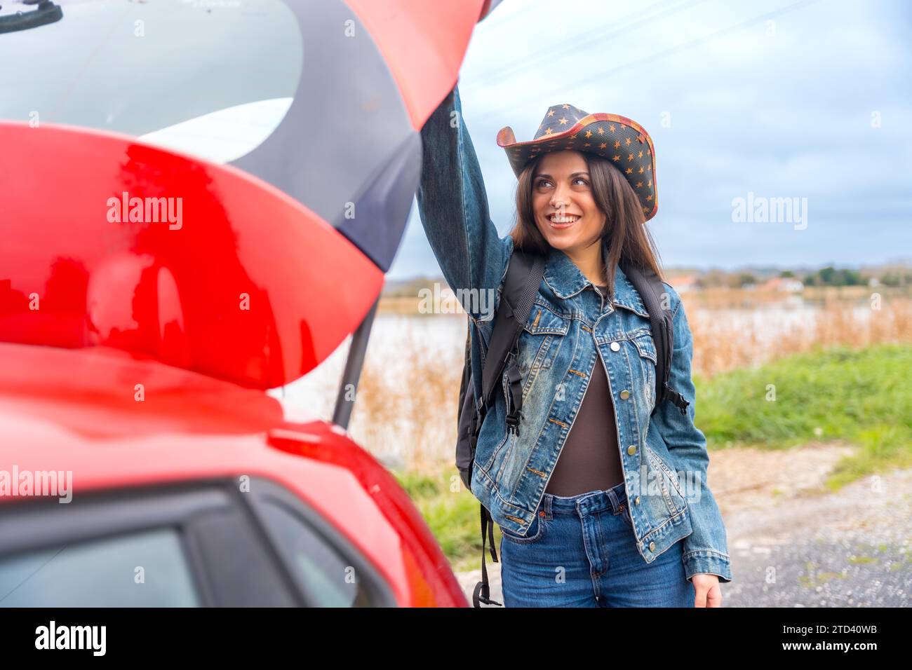 Portrait d'une aventurière heureuse voyageant avec une voiture rouge dans un Road trip Banque D'Images