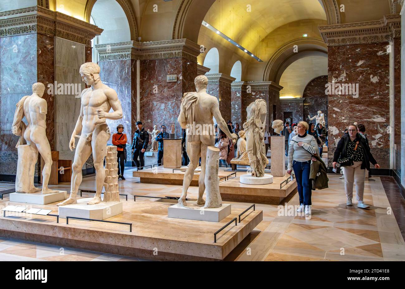 Personnes marchant à travers des statues grecques exposées à la Galerie des antiques dans l'aile Sully du Musée du Louvre à Paris, France Banque D'Images