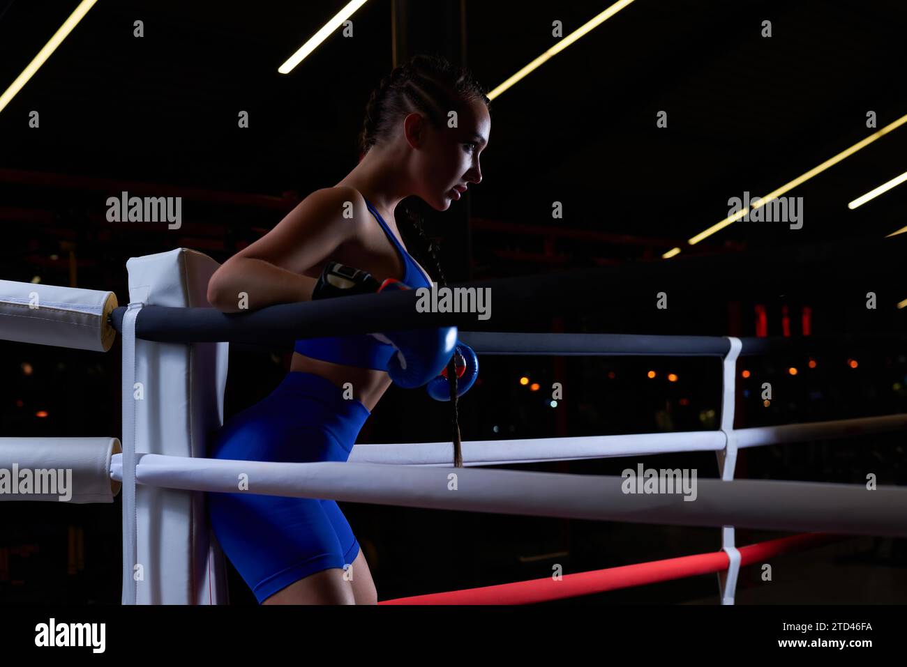 Puissante fille chargée se tient dans le coin de l'anneau et est prête à exploser dans le prochain tour. Le concept de lutte et de boxe. Supports mixtes Banque D'Images