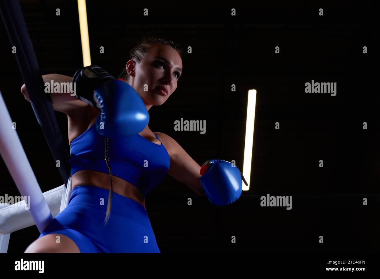 Puissante fille chargée se tient dans le coin de l'anneau et est prête à exploser dans le prochain tour. Le concept de lutte et de boxe. Supports mixtes Banque D'Images