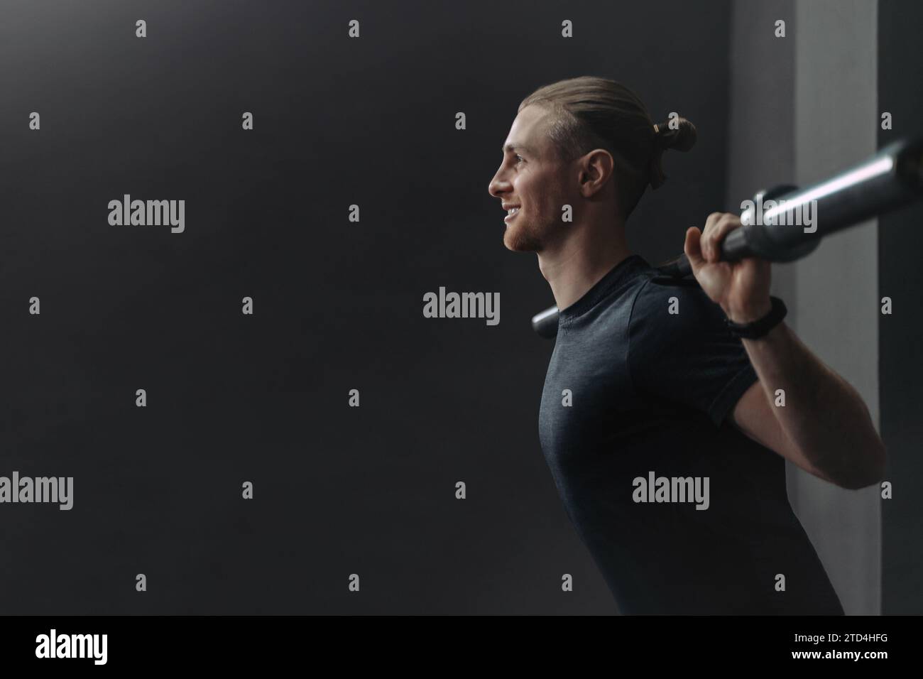 Jeune athlète crossfit beau faisant de l'exercice avec barre dans la salle de gym. Homme souriant heureux s'échauffant et se préparant avant l'entraînement. CrossFit, sport, musculation et concept de style de vie sain. Espace de copie Banque D'Images