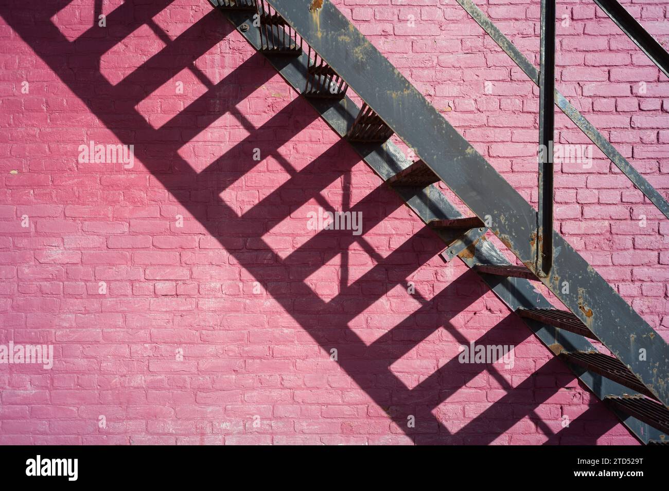 Extérieur du bâtiment avec un mur de briques roses et escalier métallique Banque D'Images