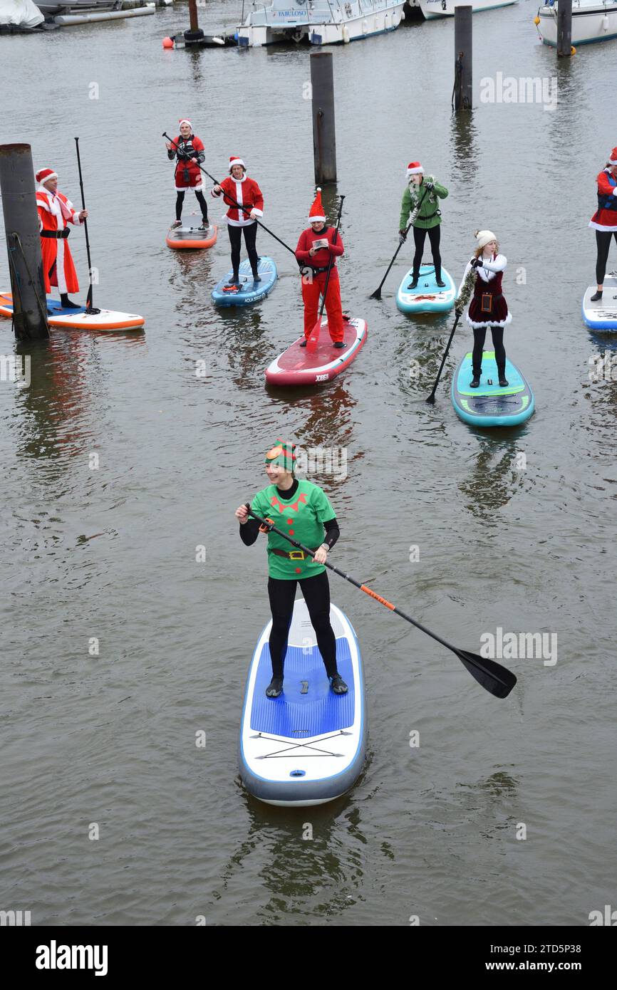 Assistant Santas avec un groupe de boarders stand-up paddle habillés en Père Noël et Elfes. Événement de Noël organisé par les BH Activity Junkies Banque D'Images