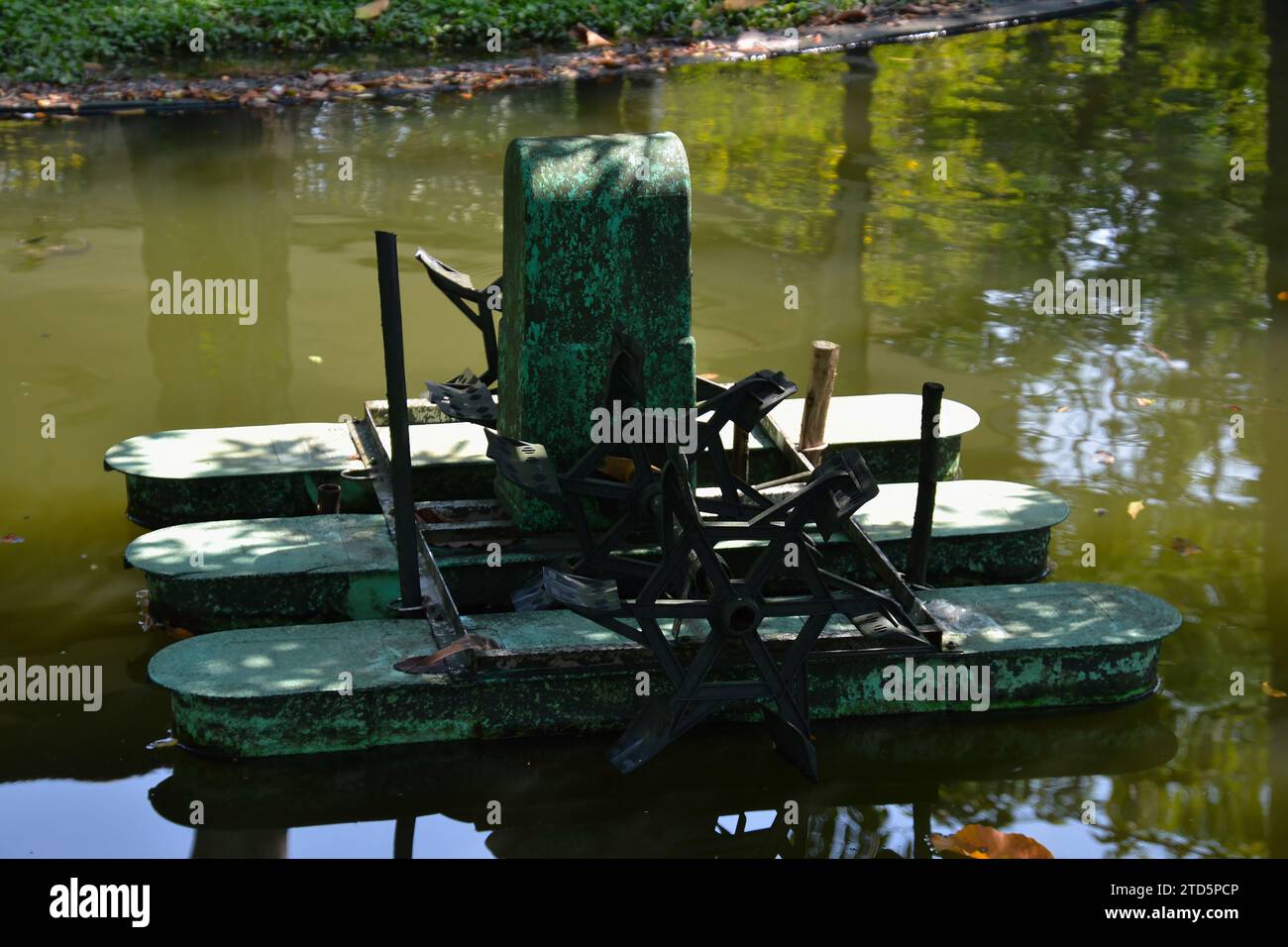 Machine à turbine à eau de style thaïlandais fonctionnant dans un étang naturel à côté d'une rizière dans la campagne de Thaïlande Banque D'Images
