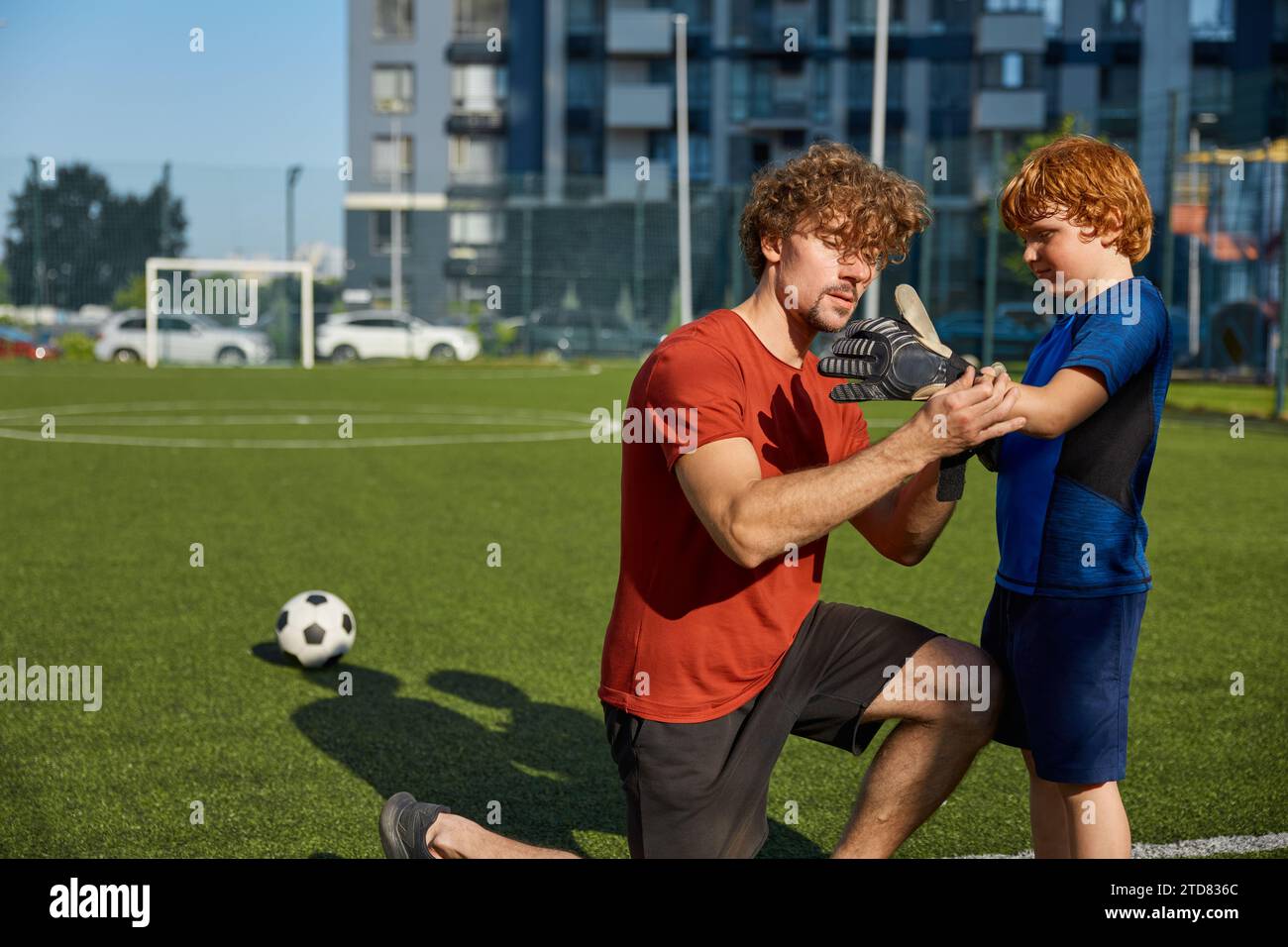 Père mettant des gants de gardien de but sur la main de son fils avant d'entraîner le football Banque D'Images