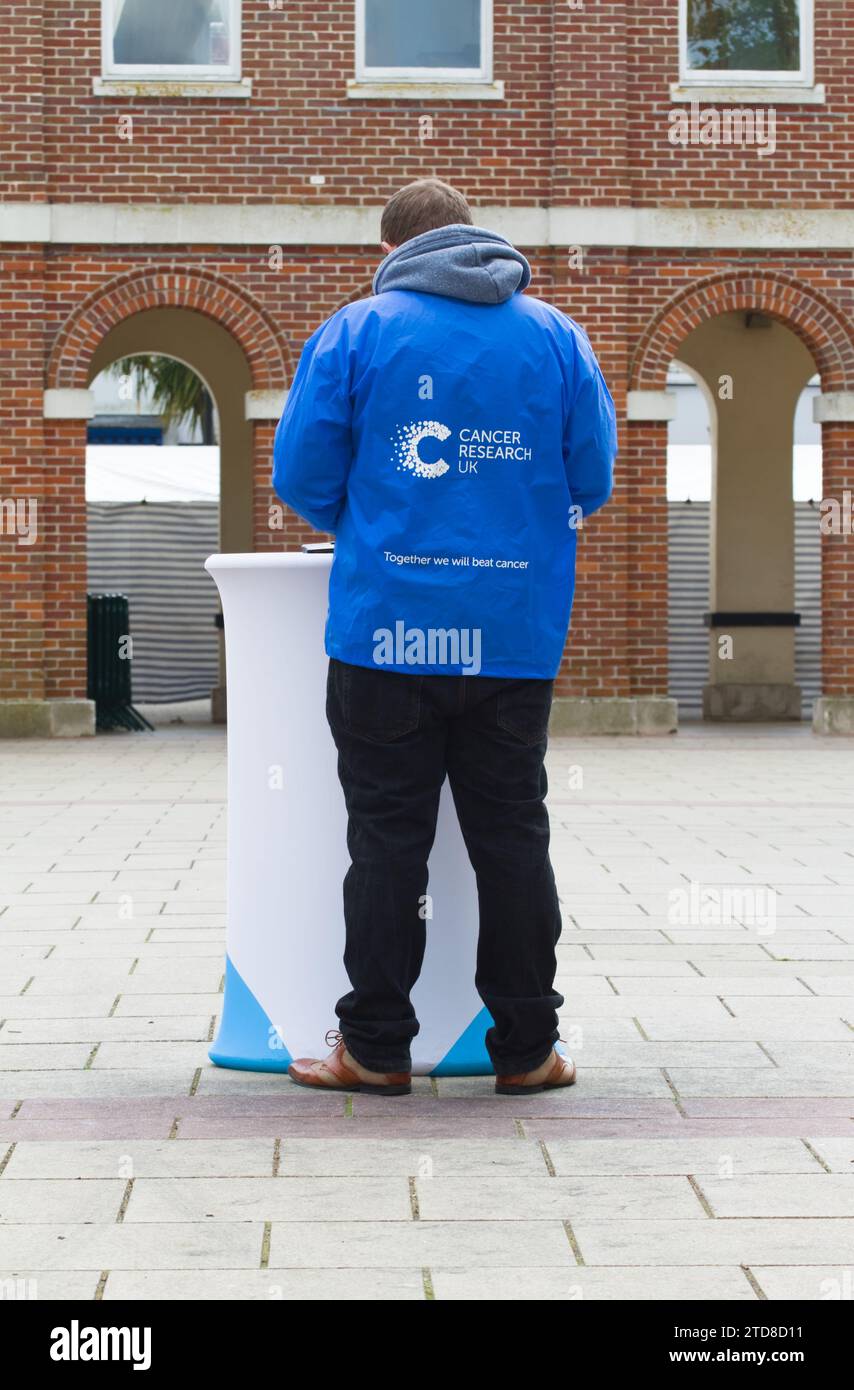 Volunteer cancer UK Charity Worker debout à Saxon Square, Christchurch, Royaume-Uni Banque D'Images