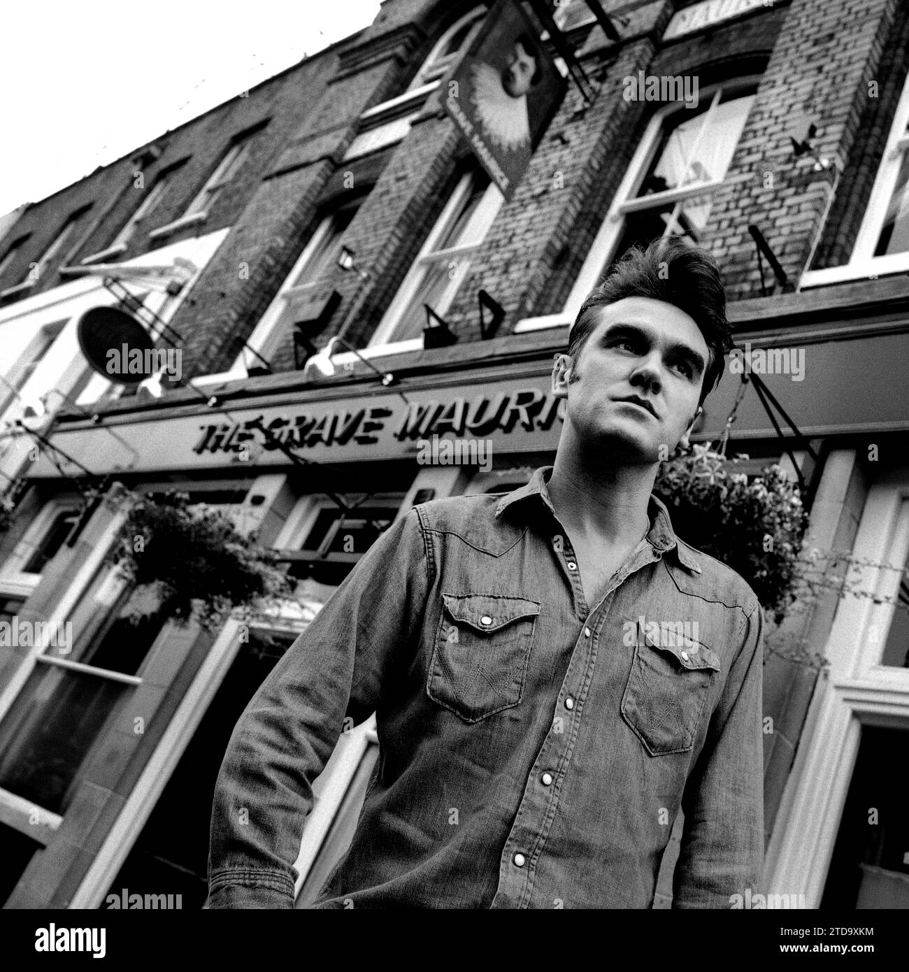 Puissant portrait noir et blanc de mi-plan de légendaire rockstar, chanteur / compositeur Morrissey en chemise en denim. Tourné dans la rue devant le pub grave Maurice, Whitechapel dans l'East End de Londres pour promouvoir son single Sunny pour Parlophone Records 1995. Banque D'Images